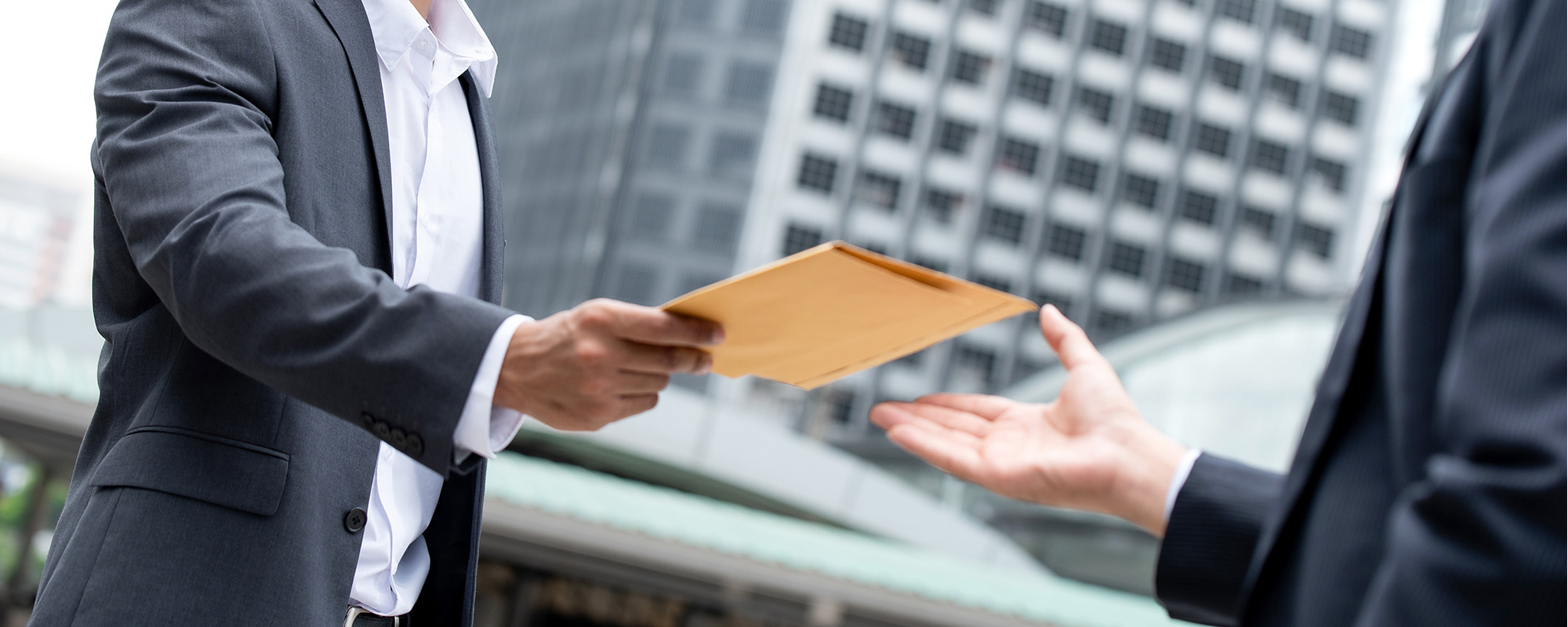 indian businessman giving document in the envelope to his partner 